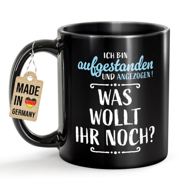 Schwarze Tasse mit Spruch - Aufgestanden und angezogen - Was wollt ihr noch?
